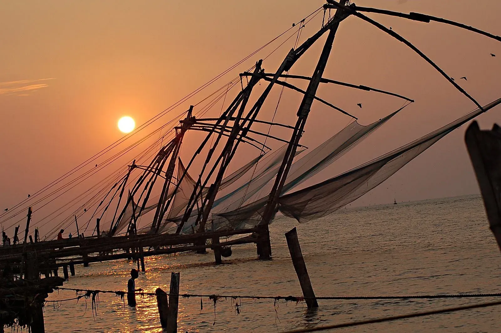Chinese fishing nets at Kochi Fort Kochi waterfront with sunset view, traditional fishing structure over Arabian Sea in Kerala