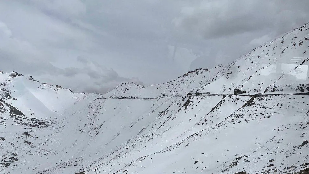 Scenic mountain road at Khardung La Pass surrounded by snow-covered Himalayan peaks in Ladakh