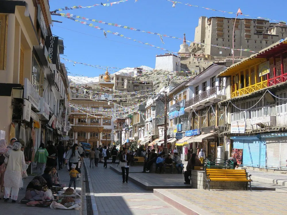 Colorful local market street in Leh Ladakh with shops, Tibetan handicrafts, cafes, and Himalayan mountain backdrop