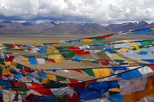Colorful Buddhist prayer flags overlooking the mountain valley and blue waters of Tso Moriri Lake in Ladakh